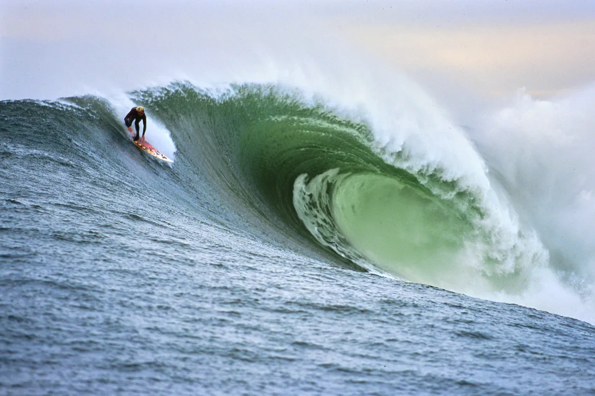 A surfer dropping into a Mavericks wave, photographed by Kai Conragan